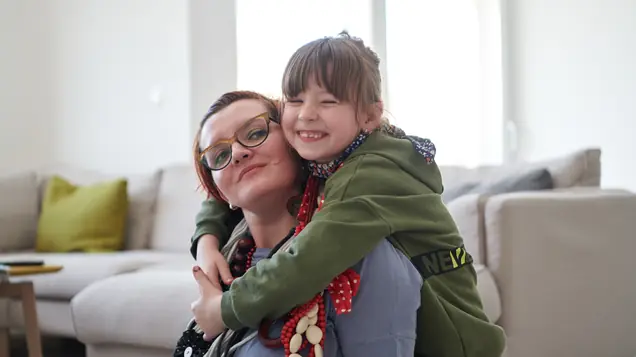 Mamma och dotter kramas i vardagsrummet