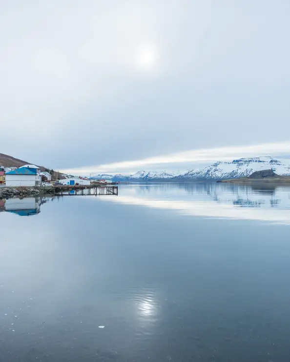 Rött hus som speglar sig i en stilla fjord