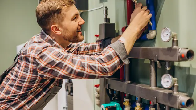 Installatör justerar fördelaren i ett vattenburet värmesystem